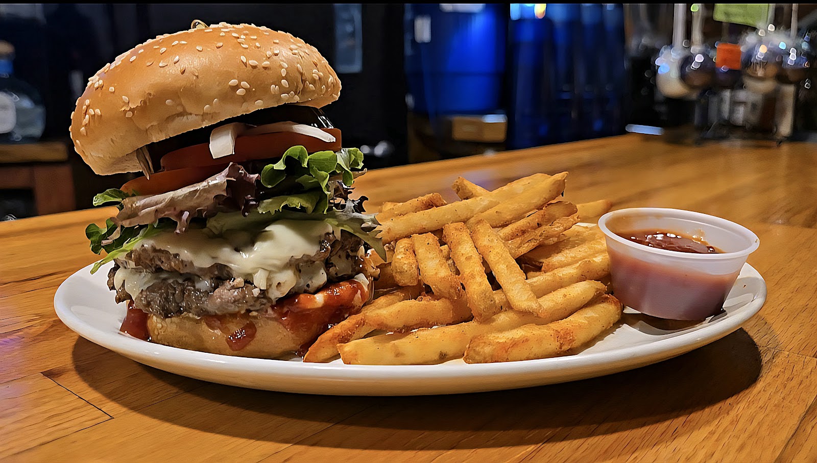 A tall double smashburger with lettuce and tomato beside a pile of golden fries.